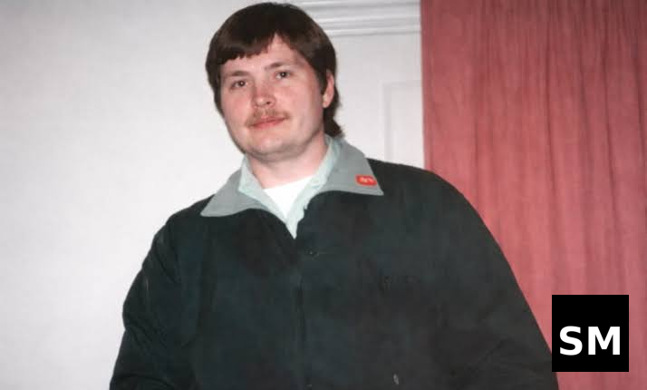 Person in dark jacket standing indoors.